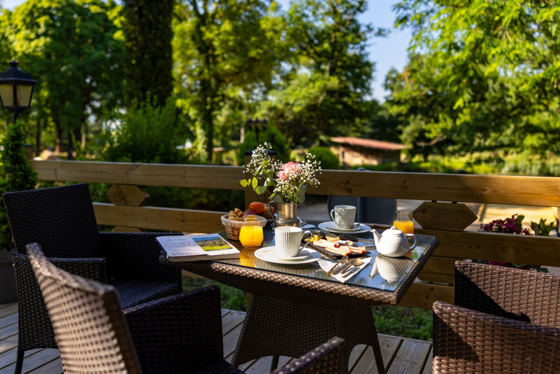Table de terrasse avec boissons et en-cas, entourée de nature verdoyante, devant le gîte Myrtille