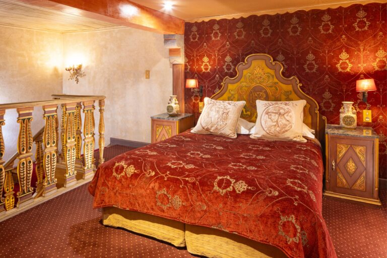 Lit avec décoration rouge et or dans la chambre Reine Victoria