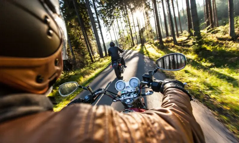 Homme conduisant une moto sur une route forestière